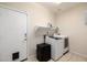 Bright laundry room with a washer, dryer, mini-fridge, utility sink, storage shelf, and convenient pet door at 6971 W El Cortez Pl, Peoria, AZ 85383