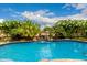 A well-maintained swimming pool surrounded by lush greenery and a rock waterfall feature under a clear sky at 6971 W El Cortez Pl, Peoria, AZ 85383
