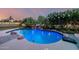 Backyard pool with a rock waterfall feature, lush landscaping, and a basketball hoop at 6971 W El Cortez Pl, Peoria, AZ 85383