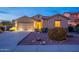 Charming exterior features desert landscaping, a two-car garage and warm lighting at 7606 E Globemallow Ln, Gold Canyon, AZ 85118