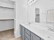 Bathroom with dual sinks, grey cabinets, large mirror, and a walk-in closet with custom shelving at 7767 W Sierra Vista Dr, Glendale, AZ 85303