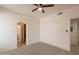 A well lit room with neutral carpet, a ceiling fan, and doorways to an ensuite and walk-in closet at 8502 E Santa Catalina Dr, Scottsdale, AZ 85255