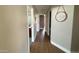 Long hallway with wood floors and neutral walls, featuring doorways to various rooms and decorative wall hangings at 984 W Belmont Red Trl, San Tan Valley, AZ 85143