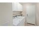 Well-lit laundry area with white appliances, tiled flooring, and storage at 10280 N 94Th Dr, Peoria, AZ 85345