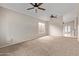 Spacious living room with neutral carpet, ceiling fans, and abundant natural light from the large window at 10280 N 94Th Dr, Peoria, AZ 85345
