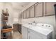 Well-lit laundry room with gray cabinets, white appliances, and spacious countertops at 14124 W Bent Tree S Cir, Litchfield Park, AZ 85340