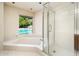 Modern bathroom featuring walk-in shower, large tub, and a view of the pool outside the window at 1562 W Las Palmaritas Dr, Phoenix, AZ 85021