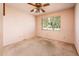 Cozy bedroom with carpeted floors, ceiling fan, and large window overlooking the front yard at 1562 W Las Palmaritas Dr, Phoenix, AZ 85021