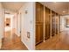 Long hallway with wood floors, featuring built in wooden cabinets and an open doorway to the living room at 1562 W Las Palmaritas Dr, Phoenix, AZ 85021
