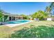 Sparkling pool surrounded by green lawn and mature trees, creating a private backyard oasis at 1562 W Las Palmaritas Dr, Phoenix, AZ 85021