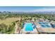 Bright aerial view of a community pool, tennis courts, and surrounding green spaces with the city skyline in the distance at 1814 W Thomas Rd, Phoenix, AZ 85015