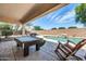 Covered poolside patio featuring a pool table, rocking chair, and view of the backyard oasis at 2016 S 102Nd Ln, Tolleson, AZ 85353