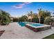 Spacious backyard with a pool and spa, outdoor kitchen, and lush desert landscaping at sunset at 2094 E Aris Dr, Gilbert, AZ 85298