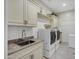 Bright laundry room features tile flooring, white cabinets, sink, countertop, washer and dryer at 2094 E Aris Dr, Gilbert, AZ 85298