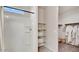 Bright bathroom featuring a shower, linen shelves, and plush robes hanging in an adjacent closet at 24052 W Pima St, Buckeye, AZ 85326