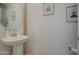 Modern powder room with pedestal sink, round mirror, and neutral decor at 2754 S Apache Dr, Chandler, AZ 85286
