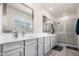 Bright bathroom features a double sink vanity, walk in shower with glass door and decorative mirrors at 286 E Raleigh Dr, Chandler, AZ 85286