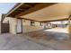 View of a large covered carport with concrete flooring, featuring a white door at 3719 W Griswold Rd, Phoenix, AZ 85051