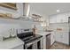 Close-up of modern kitchen with stainless steel appliances, floating shelves, and white cabinets at 3719 W Griswold Rd, Phoenix, AZ 85051
