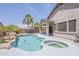 Beautiful backyard with a pool, spa, covered patio, and lush landscaping, creating an ideal setting for relaxation at 43319 W Oakland Ct, Maricopa, AZ 85138