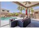 Inviting backyard featuring a covered patio, comfortable seating, palm trees, and a view of the pool at 43319 W Oakland Ct, Maricopa, AZ 85138
