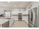 Bright kitchen features stainless steel appliances, white cabinets, and tiled backsplash at 43319 W Oakland Ct, Maricopa, AZ 85138