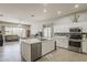Modern kitchen with stainless steel appliances, white cabinets, and an island with views of the living room at 43319 W Oakland Ct, Maricopa, AZ 85138