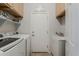 Functional laundry room with modern washer and dryer, upper cabinets, and a utility sink with storage at 43319 W Oakland Ct, Maricopa, AZ 85138
