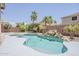 Lush backyard with a sparkling pool, rock waterfall feature, and surrounding landscaping, creating a serene oasis at 43319 W Oakland Ct, Maricopa, AZ 85138