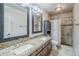 Well-lit bathroom featuring double sinks, granite countertops, dark wood cabinetry and tiled walk-in shower at 4353 W Walton Way, Chandler, AZ 85226