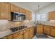 Gourmet kitchen featuring stainless steel appliances, cooktop, granite counters, and natural wood cabinets at 4353 W Walton Way, Chandler, AZ 85226