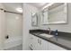 Clean bathroom with a dark countertop vanity, decorative mirror, and a shower-tub combination at 4727 E Lafayette Blvd # 211, Phoenix, AZ 85018