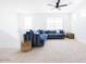Bright bonus room featuring a comfortable blue striped sectional and a modern ceiling fan at 512 E Bamboo Ln, San Tan Valley, AZ 85140