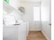 Well-lit laundry room with white washer, dryer, shelving, and wood flooring at 512 E Bamboo Ln, San Tan Valley, AZ 85140