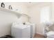 Bright laundry room features a washing machine, dryer, shelf, and natural light from a window at 512 E Bamboo Ln, San Tan Valley, AZ 85140