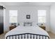 Bright primary bedroom featuring a stylish black metal bed frame and neutral decor under two large windows at 512 E Bamboo Ln, San Tan Valley, AZ 85140