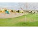 Community playground has swing sets, and a blue slide, set in a green space in this residential neighborhood at 512 E Bamboo Ln, San Tan Valley, AZ 85140