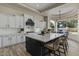 Open kitchen featuring white cabinets, a black island, and modern lighting fixture at 5827 S Marin Ct, Gilbert, AZ 85298