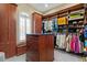 A stylish walk-in closet with wooden cabinets, shelving, central island, and a window for natural light at 5827 S Marin Ct, Gilbert, AZ 85298