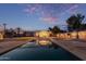 Large backyard with a pool, trees, and houses under a pretty pink sunset at 6231 E Desert Cove Ave, Scottsdale, AZ 85254