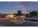Large backyard with a pool, trees, and houses under a pink sunset at 6231 E Desert Cove Ave, Scottsdale, AZ 85254