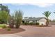 Well-maintained single-story house with brick accents, lush shrubs, and a winding circular driveway to the two-car garage at 6231 E Desert Cove Ave, Scottsdale, AZ 85254