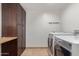 Convenient laundry room with appliances, dark wood cabinets, butcher block folding table and tile floors at 6231 E Desert Cove Ave, Scottsdale, AZ 85254