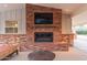 Outdoor fireplace with brick surround, mounted television, and a covered patio seating area at 6231 E Desert Cove Ave, Scottsdale, AZ 85254