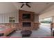 Covered patio with brick fireplace, tv, and ceiling fan at 6231 E Desert Cove Ave, Scottsdale, AZ 85254
