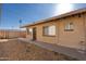 Side exterior view of the tan apartment building with a security door, multiple windows, and gravel at 7101 N 36Th Ave # 102, Phoenix, AZ 85051