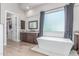 Modern bathroom with freestanding tub, granite vanity, walk-in closet and wood-look flooring at 8725 E Menlo Cir, Mesa, AZ 85207