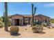 Desert landscaping enhances this tan home featuring a tile roof and stone accents on the columns and entry at 8725 E Menlo Cir, Mesa, AZ 85207