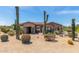 Desert landscaping enhances this tan home featuring a tile roof and stone accents on the columns and entry at 8725 E Menlo Cir, Mesa, AZ 85207