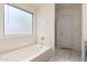 Bathroom showcasing a relaxing tub with a frosted window and tiled walls at 13241 W Desert Ln, Surprise, AZ 85374